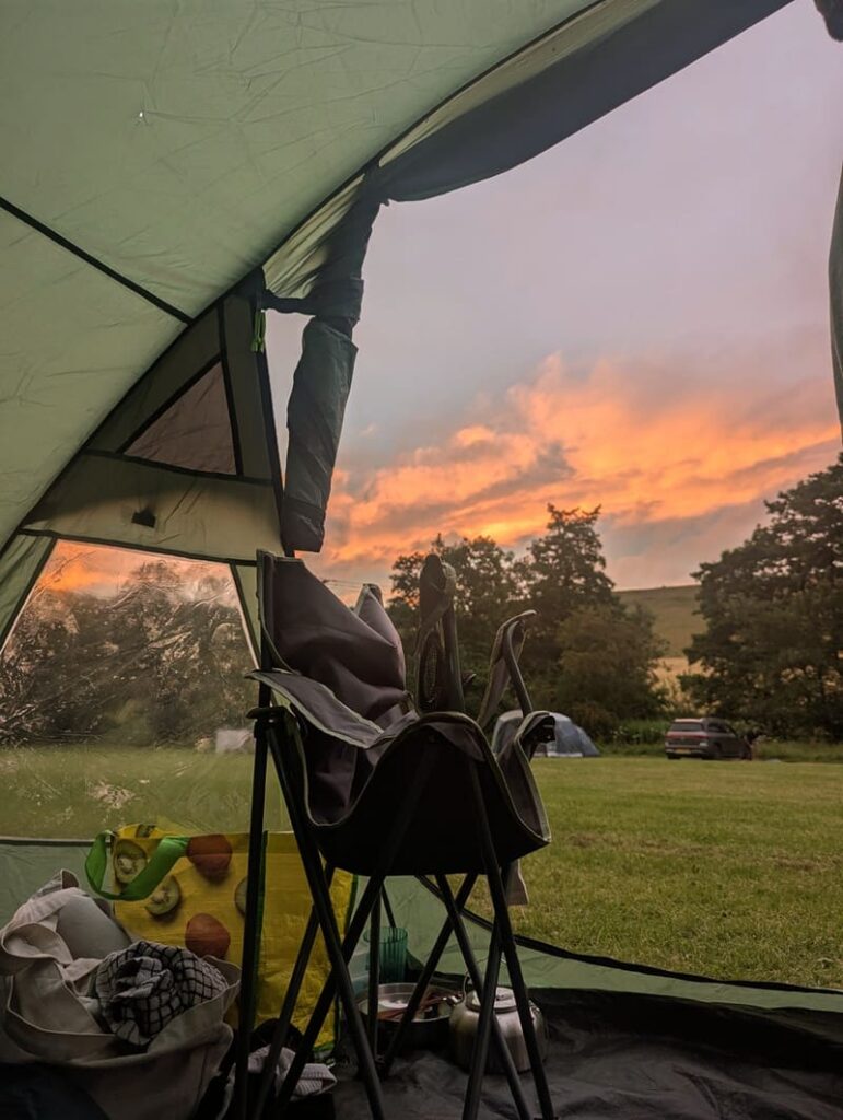 Sunset view from a tent at a countryside campsite in Pickering, North Yorkshire, with soft evening light over the English countryside.