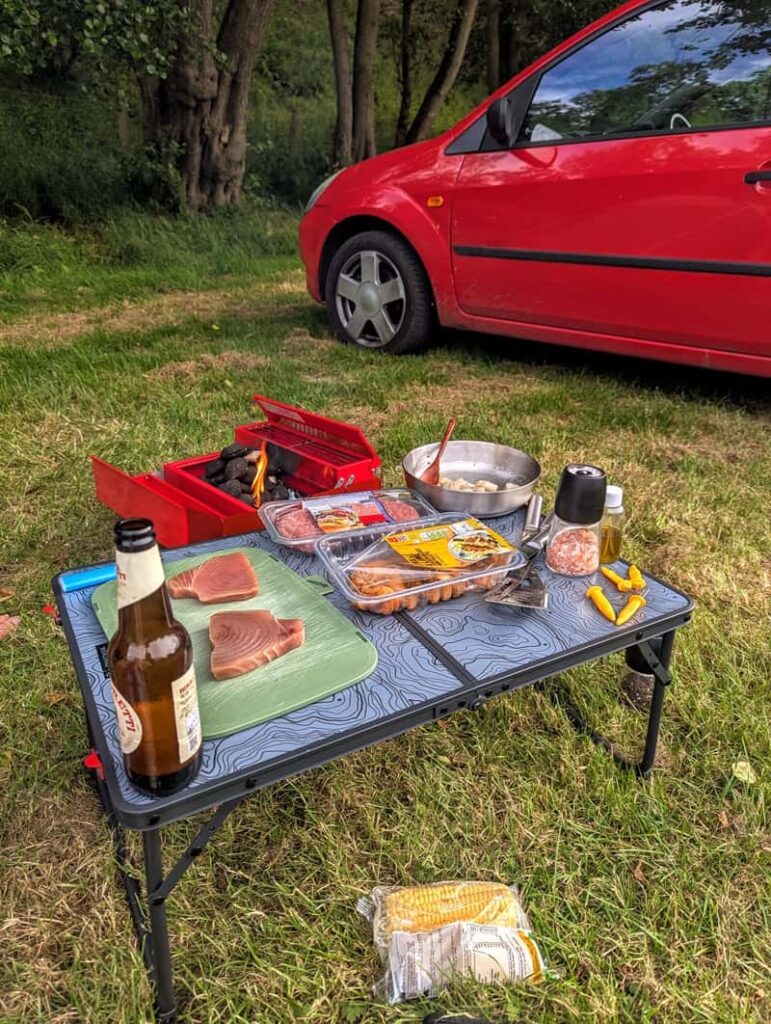 Campsite view of a toolbox BBQ with fresh produce and drinks at a countryside campsite in Pickering, North Yorkshire.