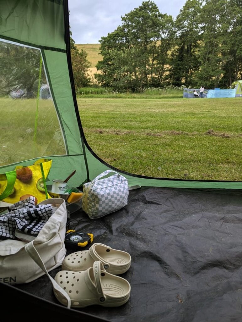 Sunrise view from a tent at a countryside campsite in Pickering, North Yorkshire, with soft morning light over the English countryside.